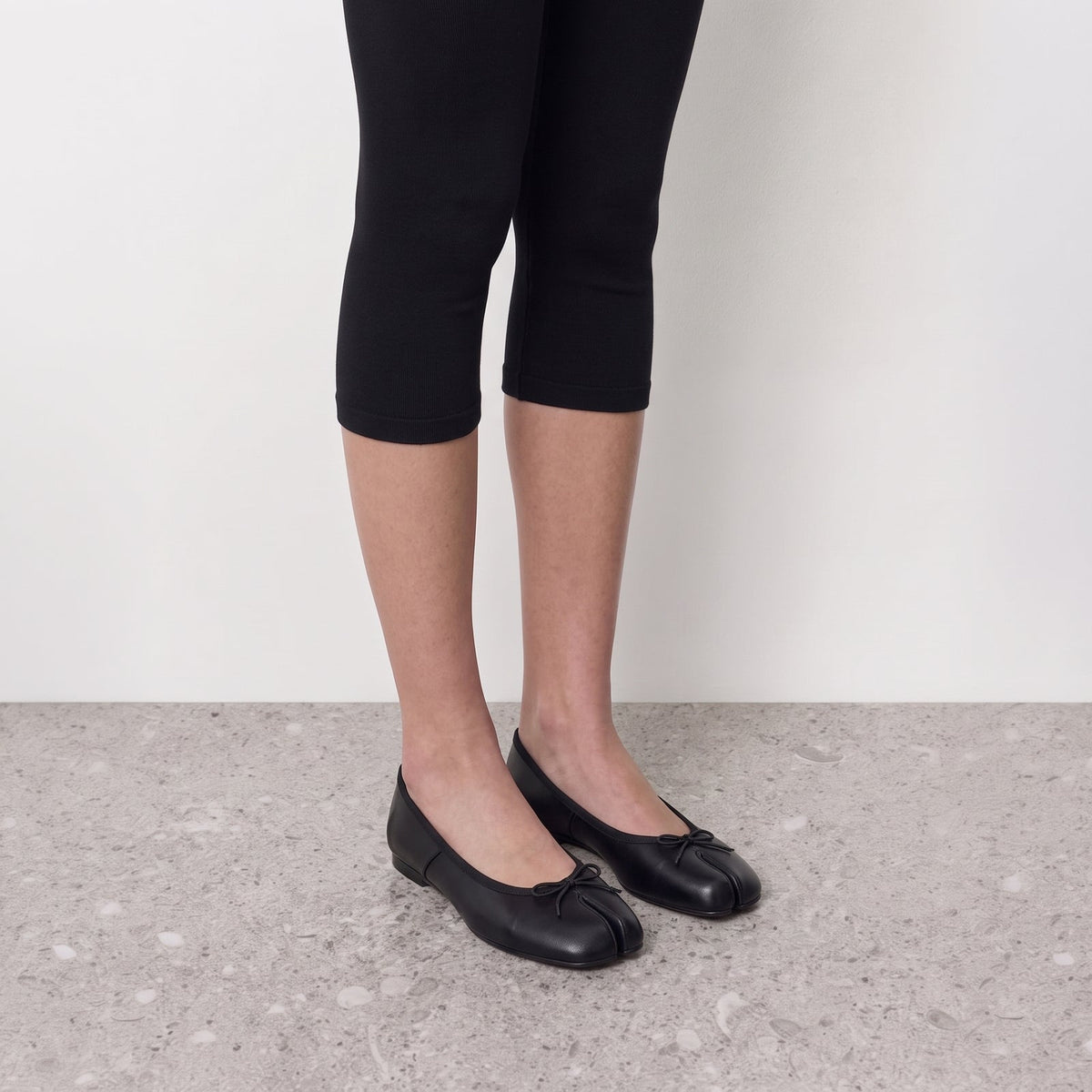 Evelyne Black Satin Tabi Ballet Flats by Lil Cacti — on-model styled with black cropped leggings on a grey terrazzo floor