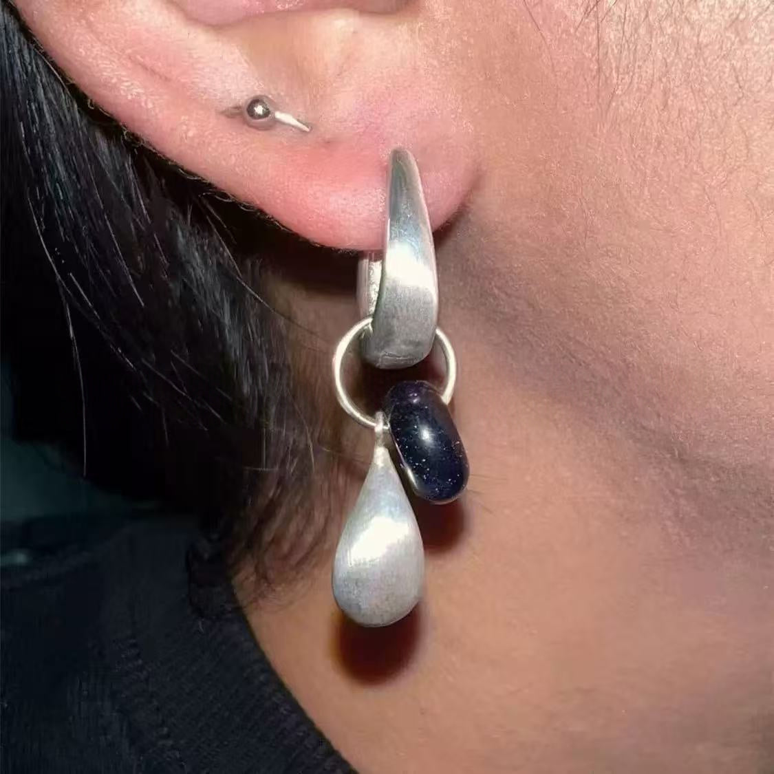 Close-up of the Dew Teardrop Charm Hoop Earrings, showing the finish and shape up close