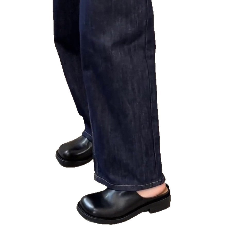 Model wearing black square-toe mules with jeans, walking pose
