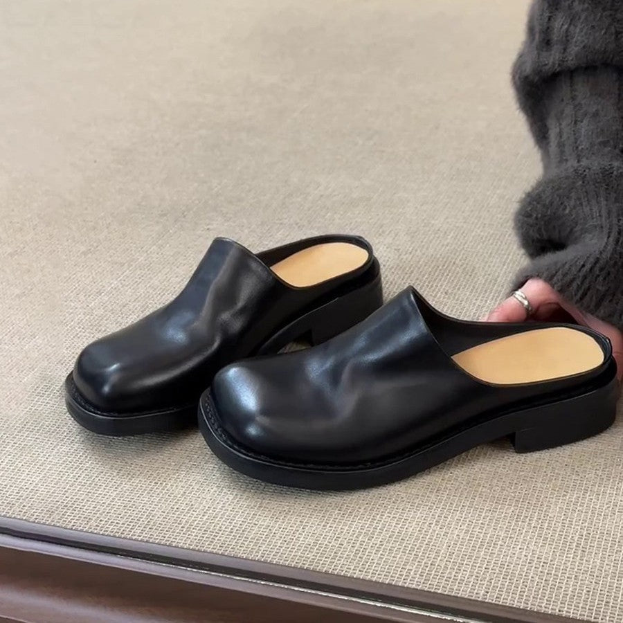 Black square-toe mules on a beige rug, tan insole visible