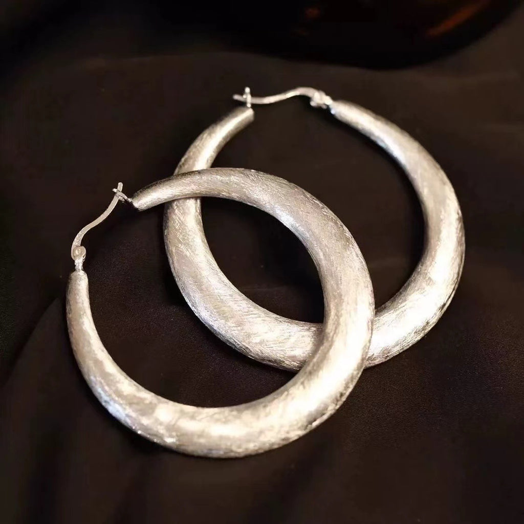 Detail view of the Tide Hammered Hoop Earrings, chunky silver-tone hoop earrings