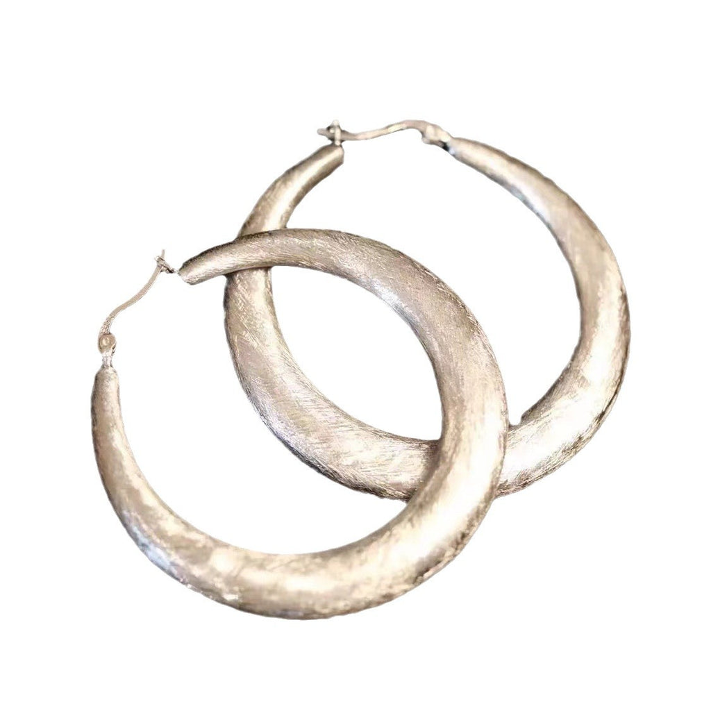 Tide Hammered Hoop Earrings styled on the ear with a plain black outfit