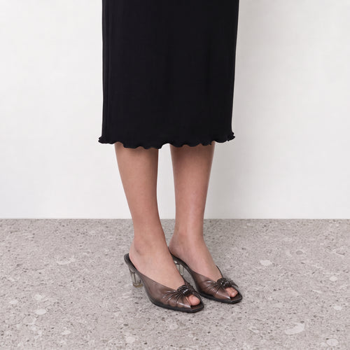Amara Jelly Mule by Lil Cacti — on-model in black with a black lettuce-hem midi dress, bare legs, terrazzo floor
