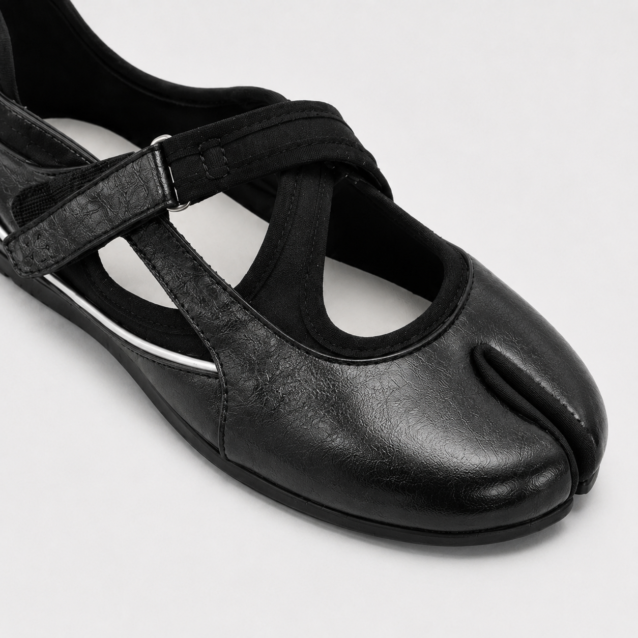 Three quarter view of black cross strap tabi flats showing the low side profile