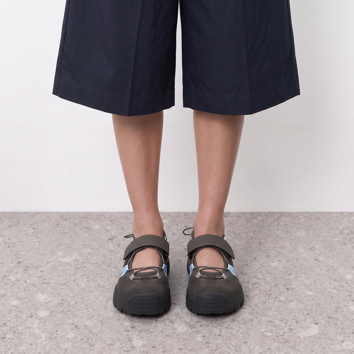 Front view on the foot of grey mary jane sneakers with blue bungee lacing
