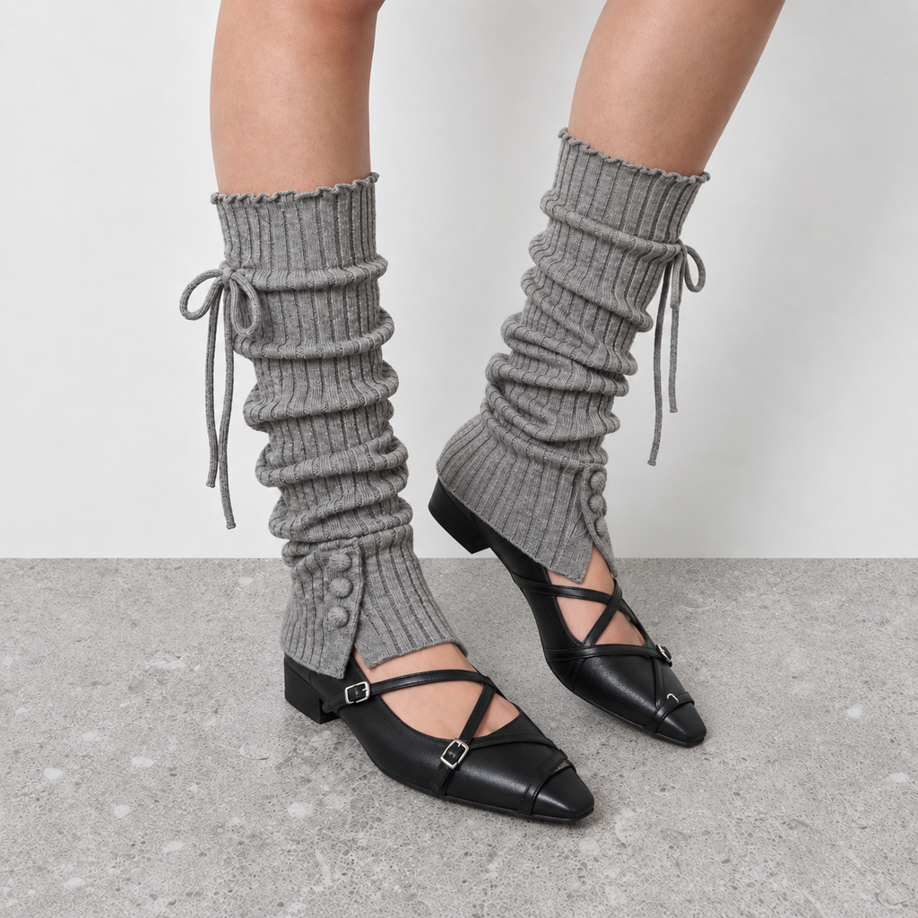 Grey knitted leg warmers slouched over the ankle above black flats