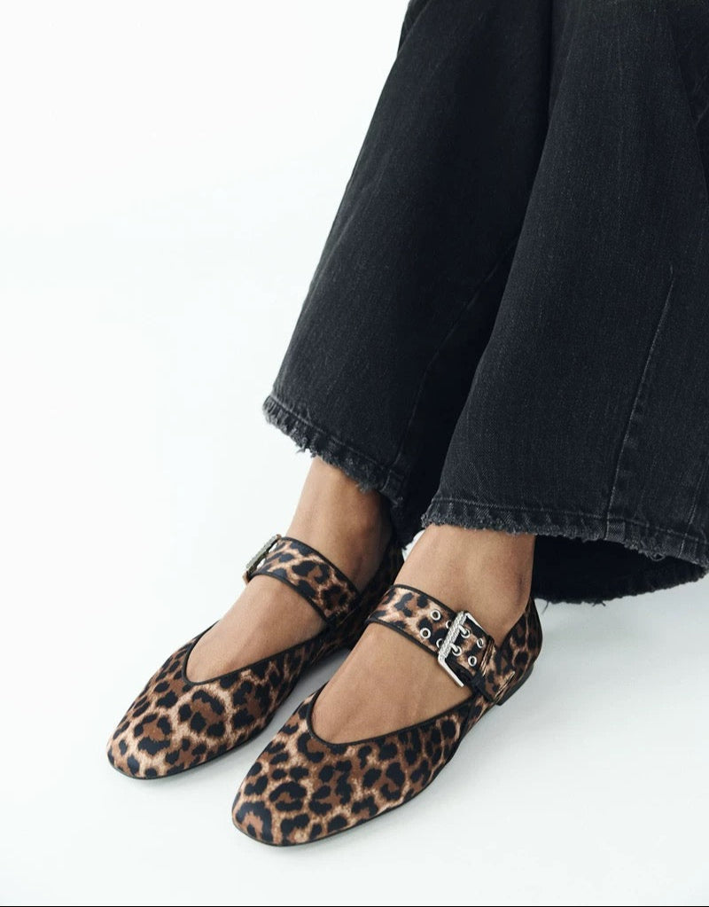 Person wearing leopard print shoes with a white background