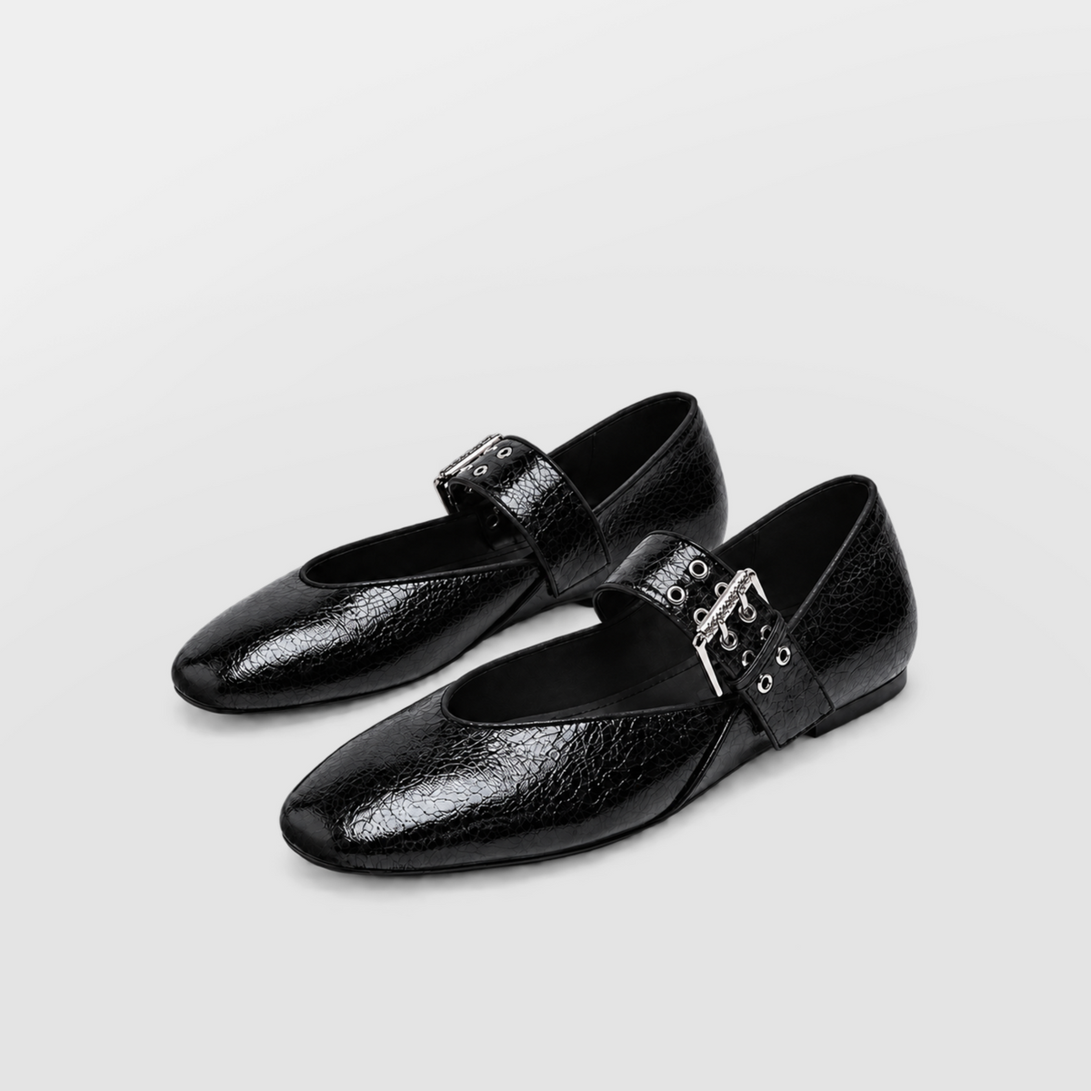 Pair of black buckled mary jane flats angled on a white background