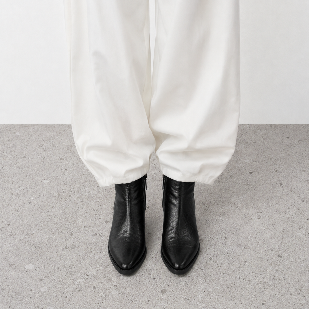 Brown pointed toe western boots styled on a rug beside an open book