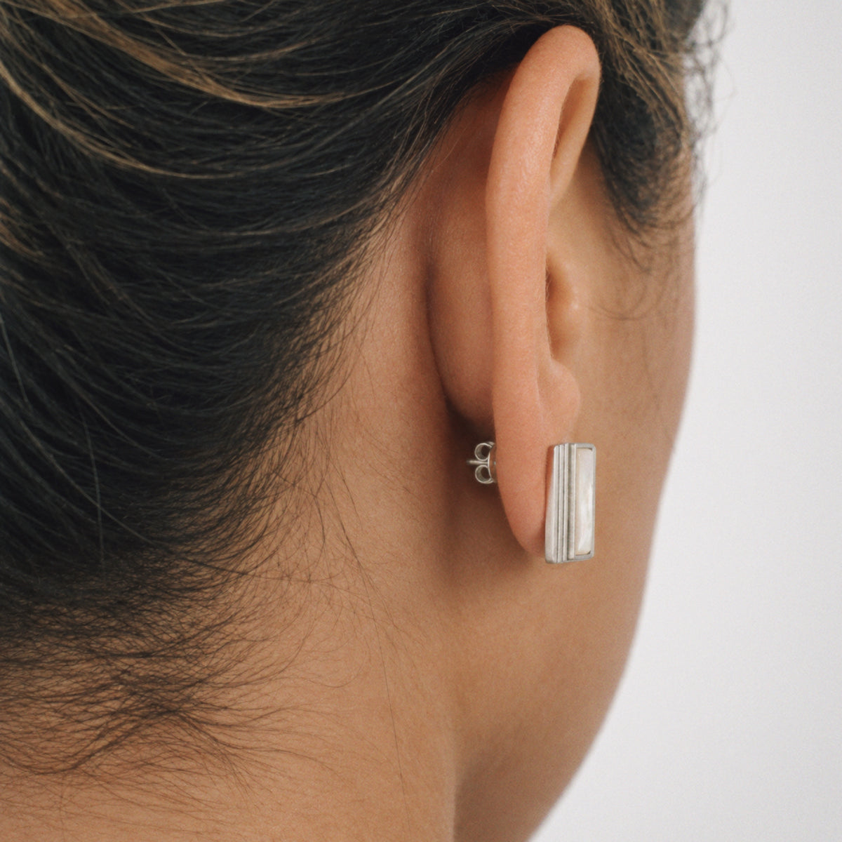 Model wearing the Column Square Stud Earrings, three quarter view