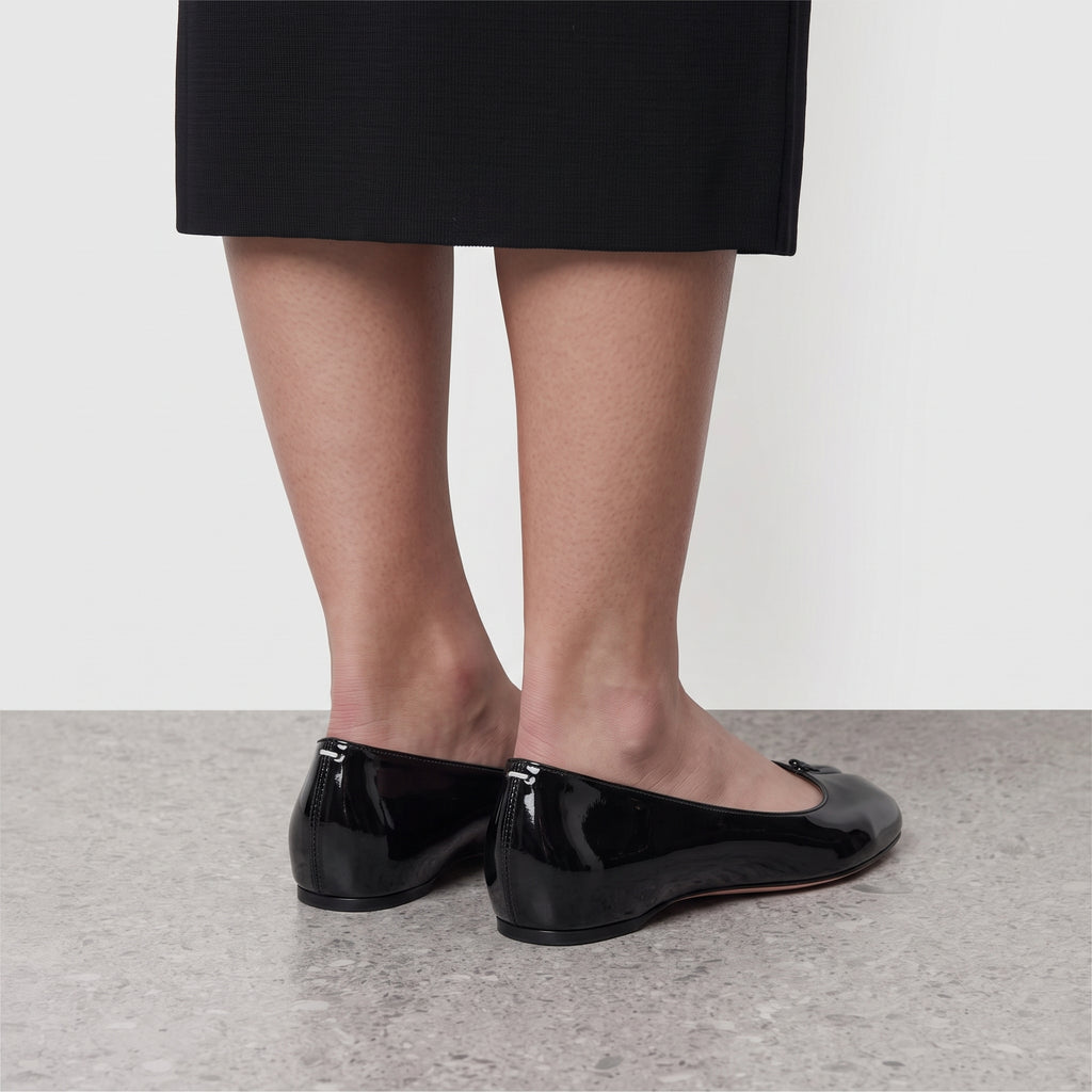 Model standing in Lil Cacti Echo black patent tabi flats