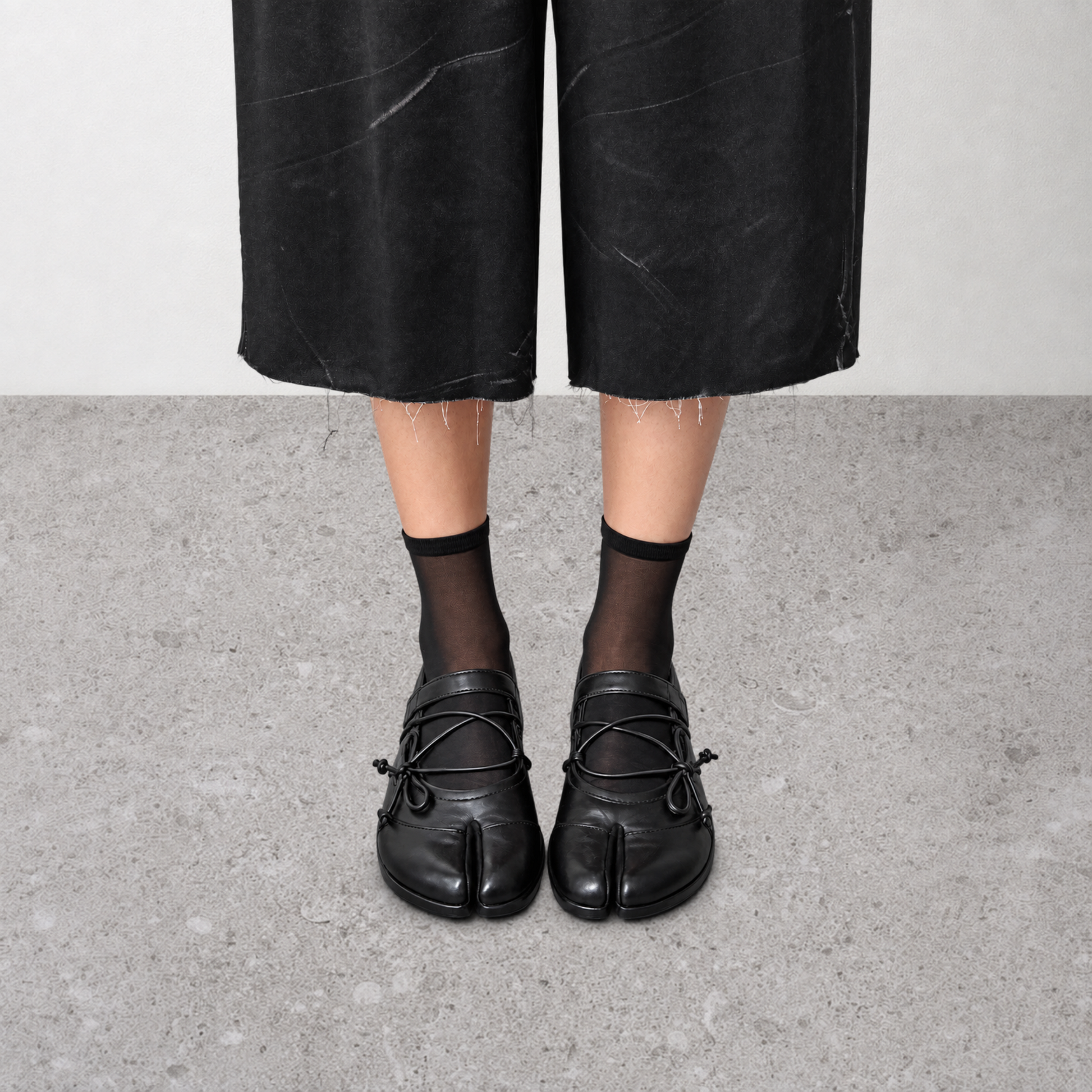 Side profile of a single black leather ballet flat with cord lacing
