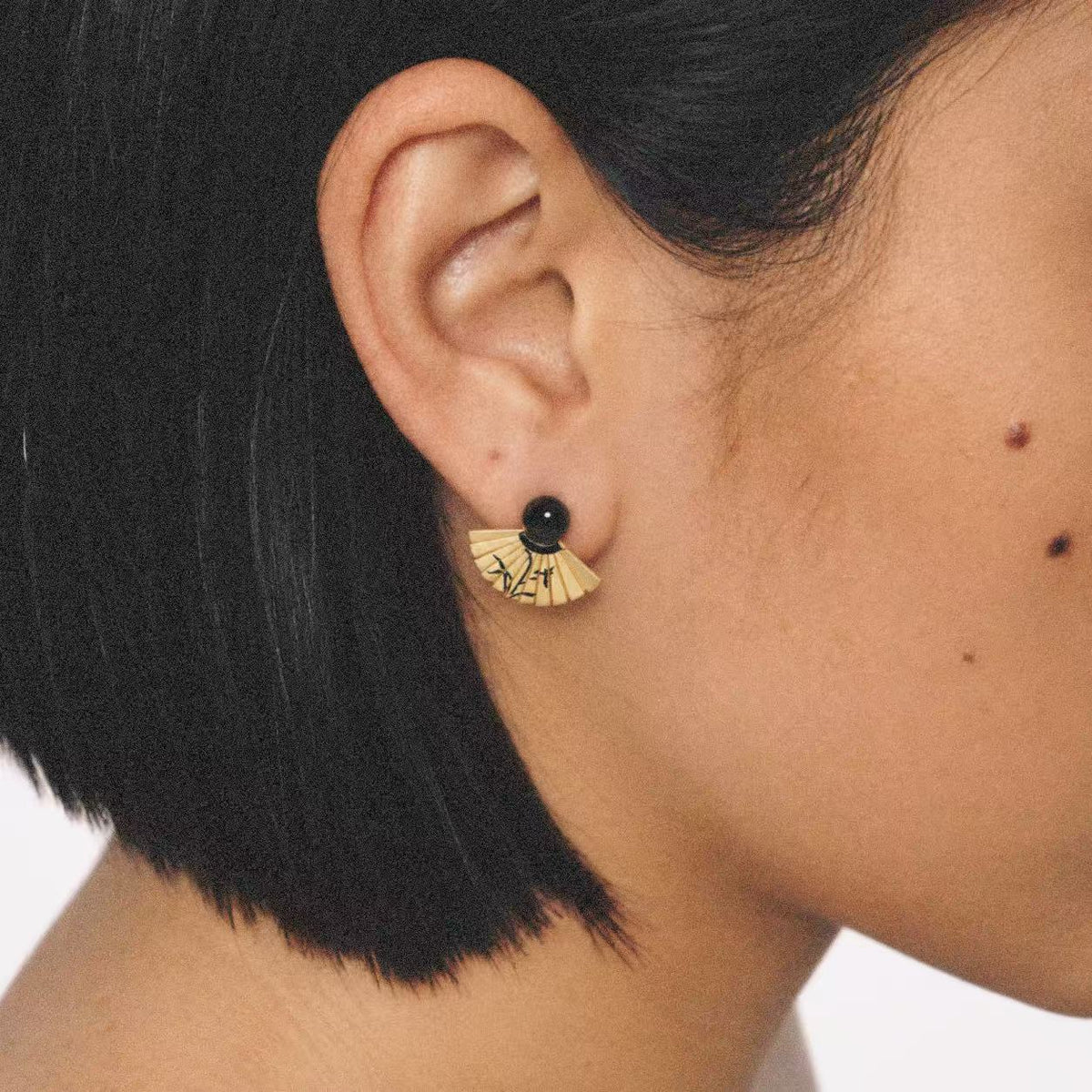 Model wearing the Etched Fan Drop Earrings in a relaxed pose