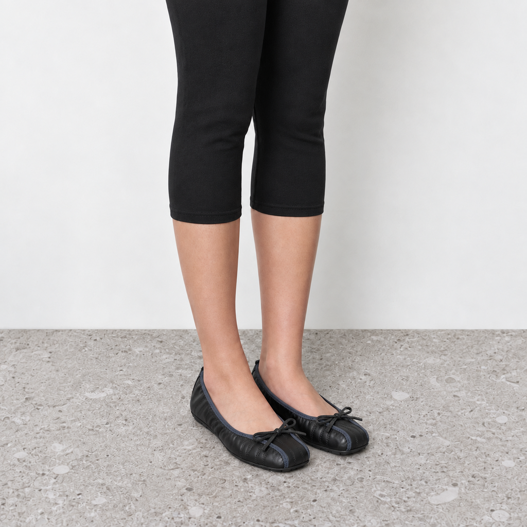 Model wearing Faye Ruched Bow Ballet Flats in black, angled on-foot product view