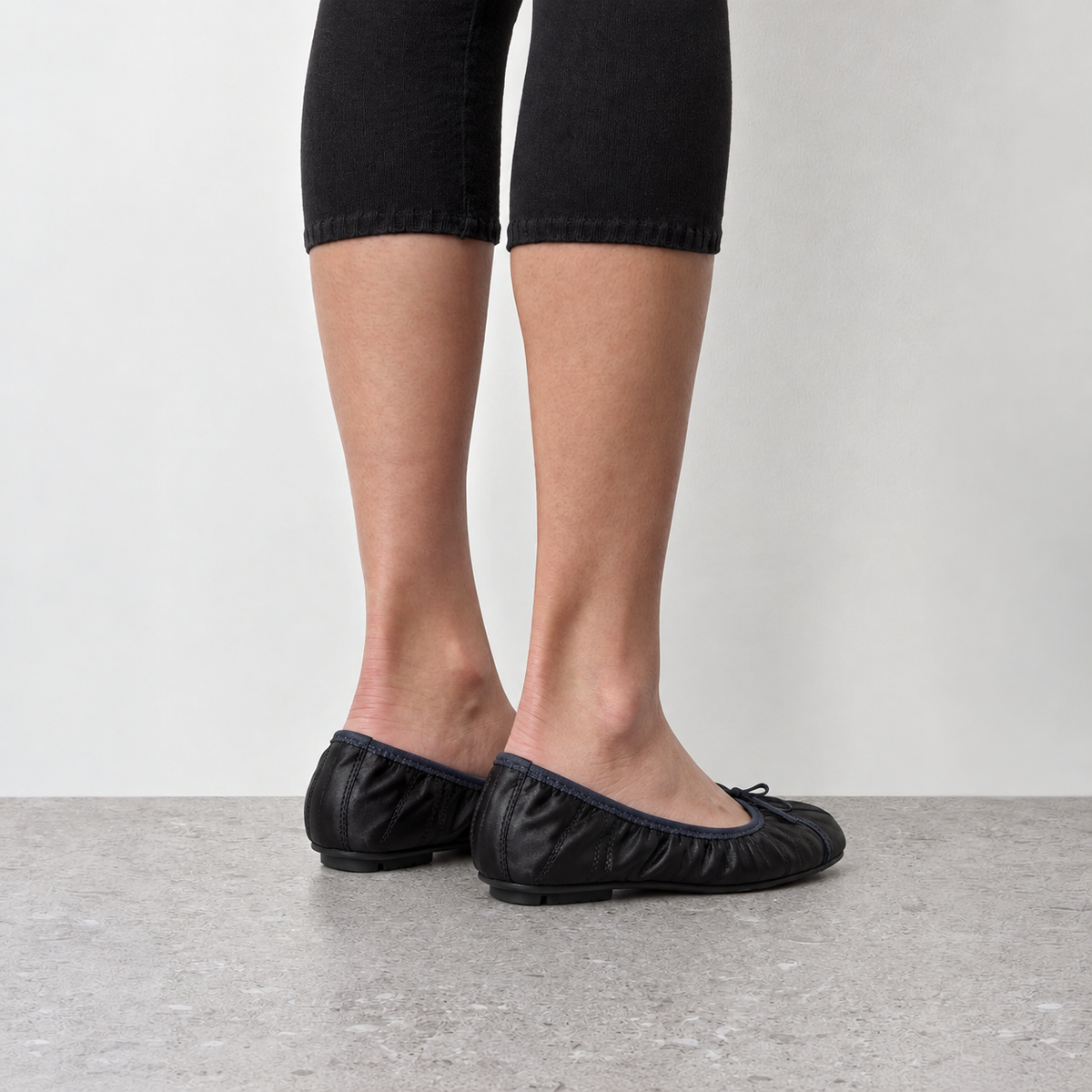 Model wearing Faye Ruched Bow Ballet Flats in black, close on-foot styling detail