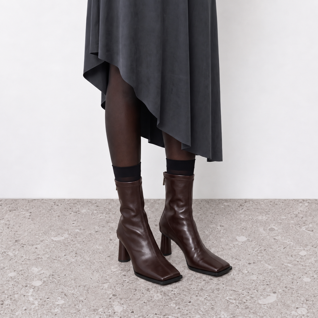 Brown stretch sock boots worn under a grey draped midi skirt