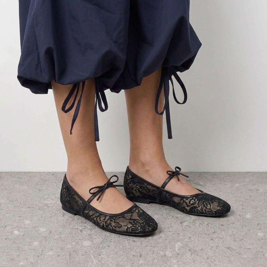 Model wearing black lace ballet flats with a slim bow-tied strap