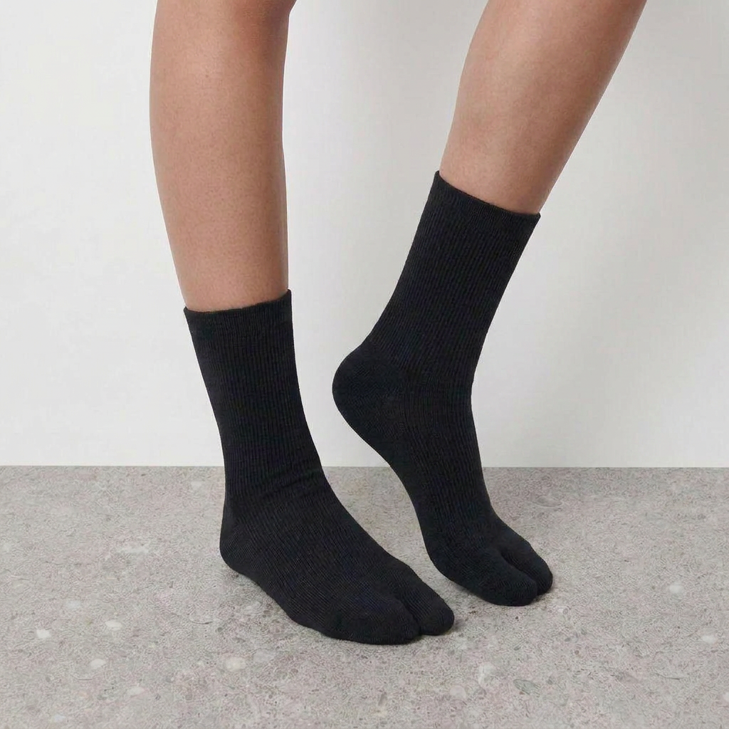 Mid Calf Tabi Socks by Lil Cacti — black pair on model, back foot raised on tiptoe to show the split toe