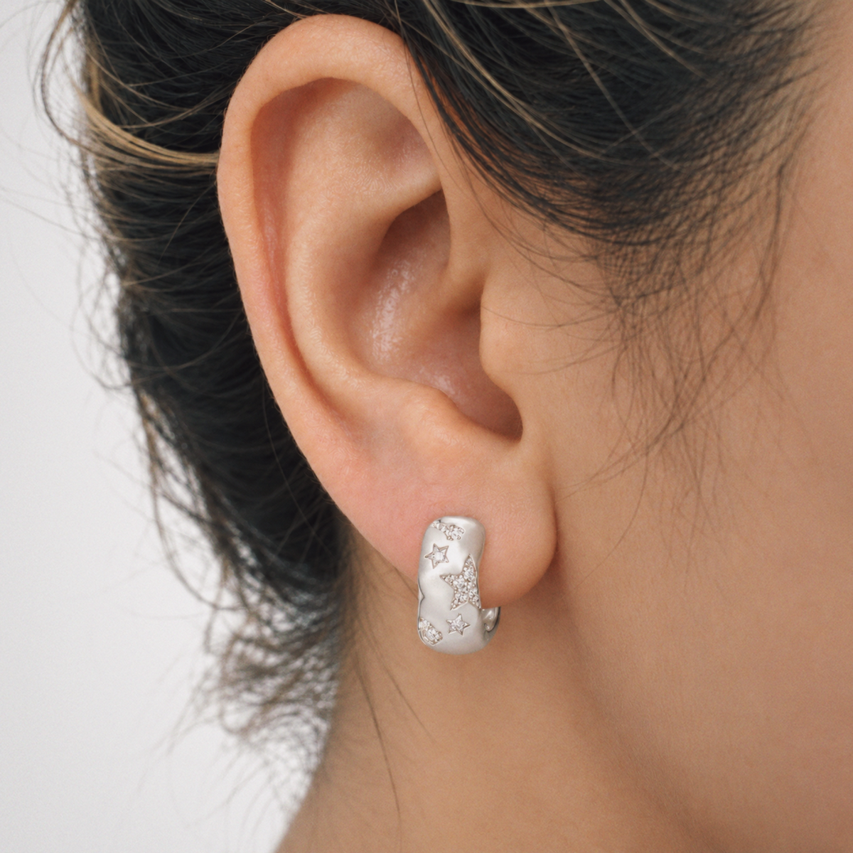 Model wearing Lil Cacti star huggie earrings in a close detail view