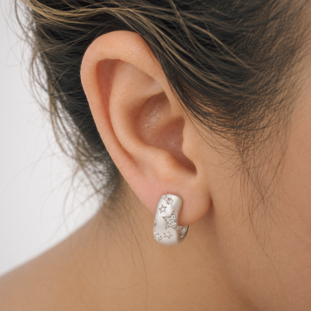 Model wearing Lil Cacti star huggie earrings in a close detail view