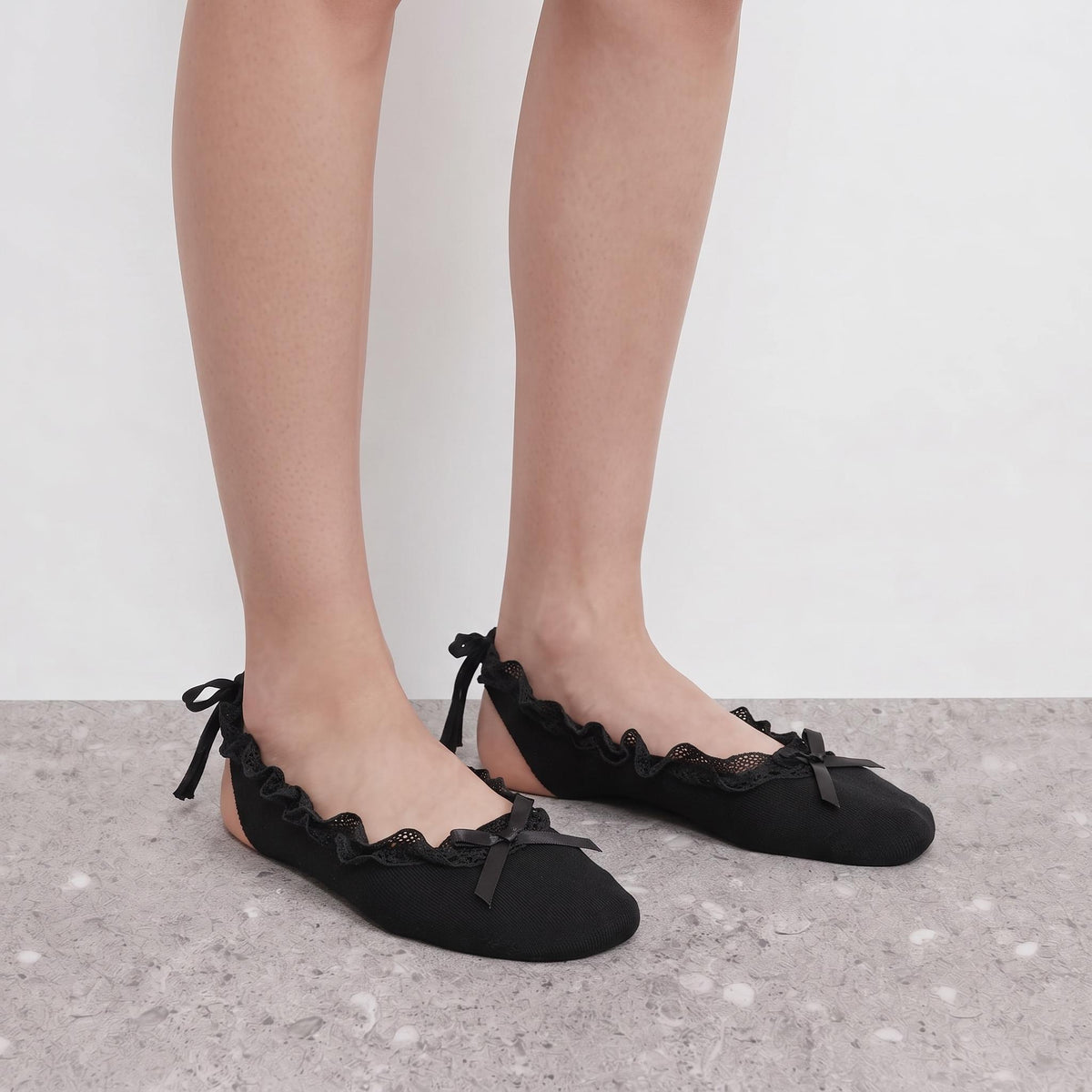Model wearing black ruffle ballet socks with crossed ankle ribbon ties