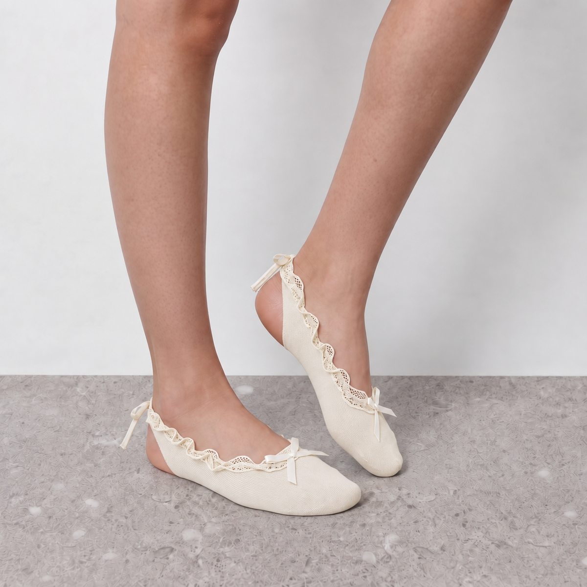 Cream ruffle ballet socks worn with one foot lifted, showing ribbon ties