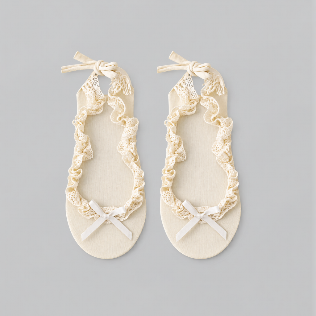 Pair of cream ruffle ballet socks laid flat with lace trim and bows