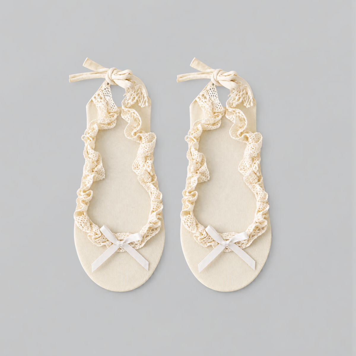Pair of cream ruffle ballet socks laid flat with lace trim and bows