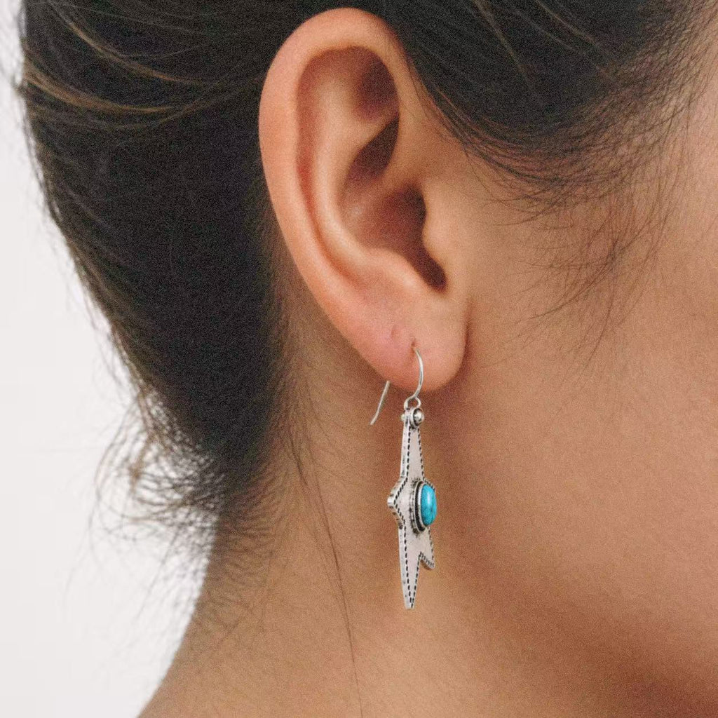 Halcyon Western Star Earrings styled on the ear with a plain black outfit