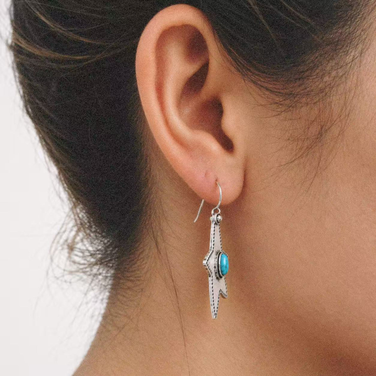 Halcyon Western Star Earrings styled on the ear with a plain black outfit
