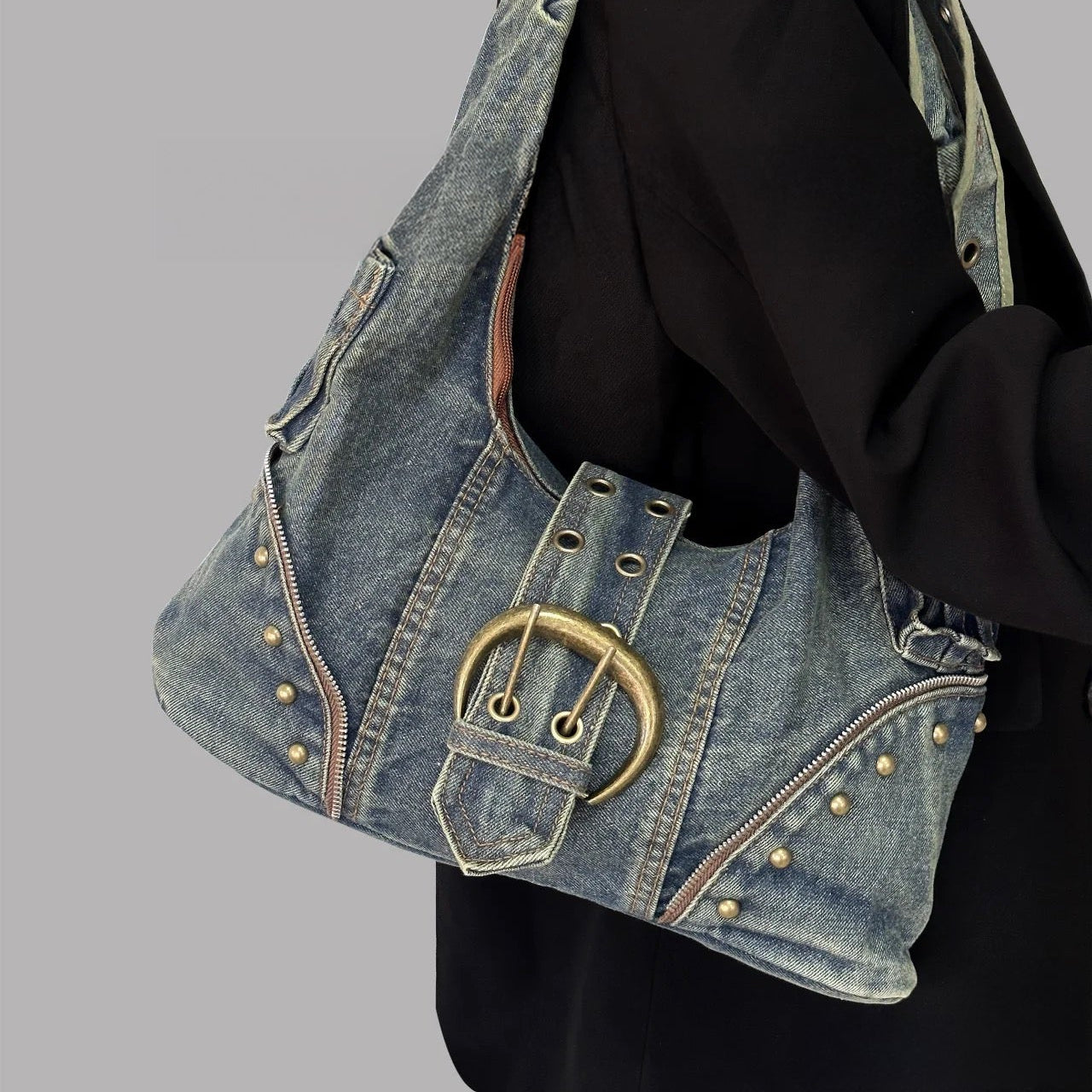 Denim handbag with gold buckle on a gray background