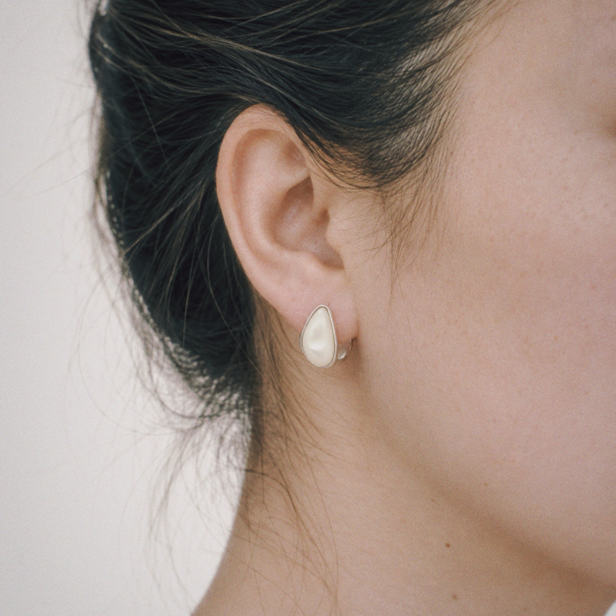 Model wearing the Lune Chunky Huggie Earrings from a side angle