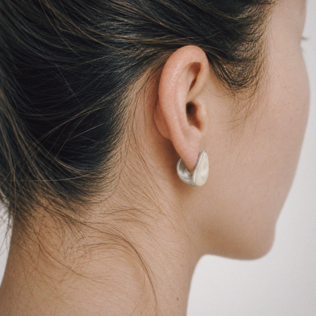 Model wearing the Lune Chunky Huggie Earrings, three quarter view