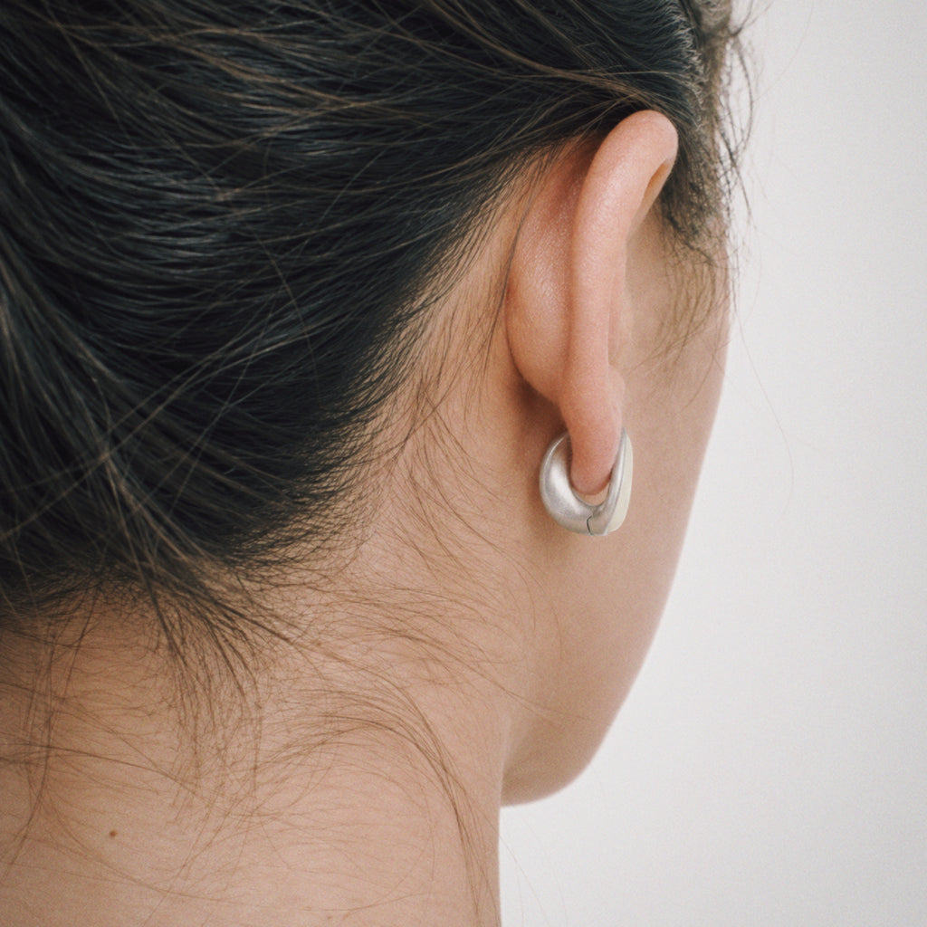 Model wearing the Lune Chunky Huggie Earrings in soft daylight