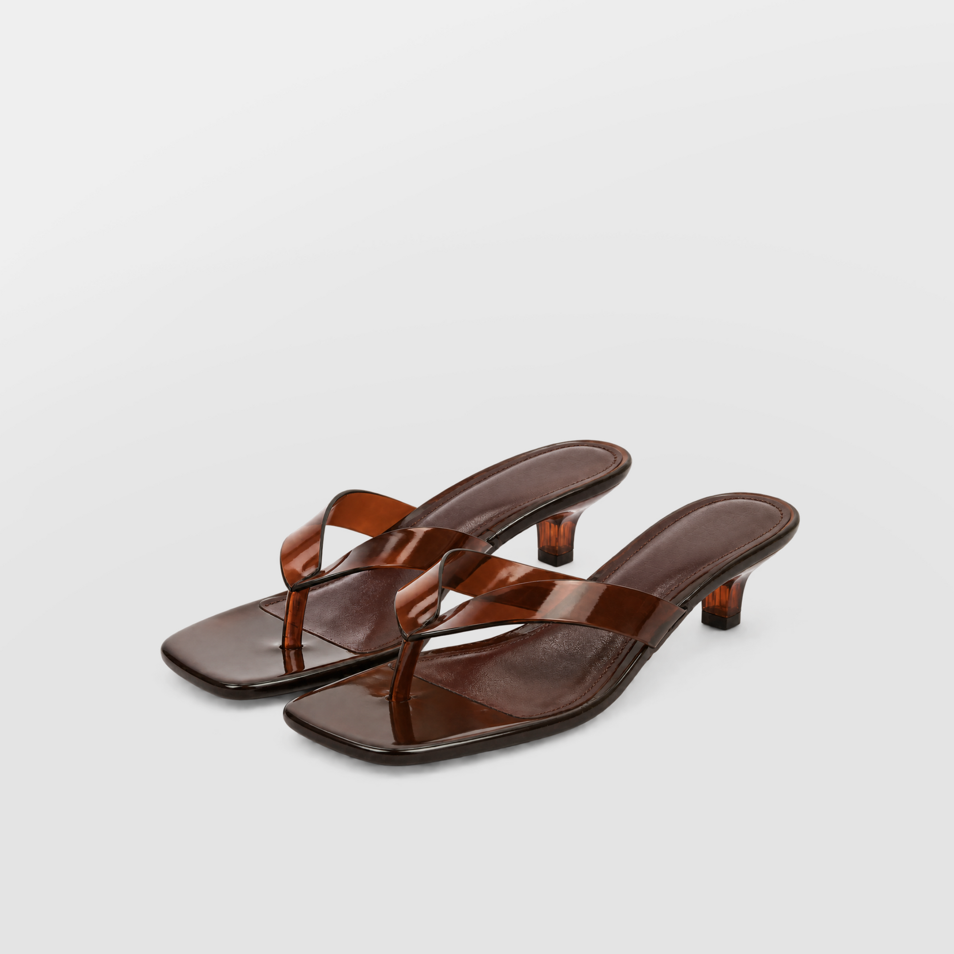 Mirage Thong Sandals by Lil Cacti — brown pair three-quarter view showing glossy amber thong straps and kitten heels