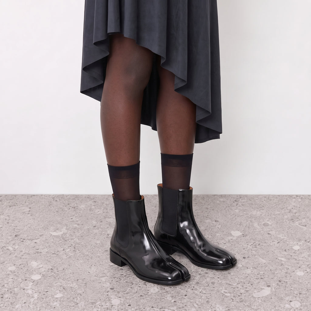 Nadia black tabi Chelsea boots worn with sheer socks and a grey draped skirt