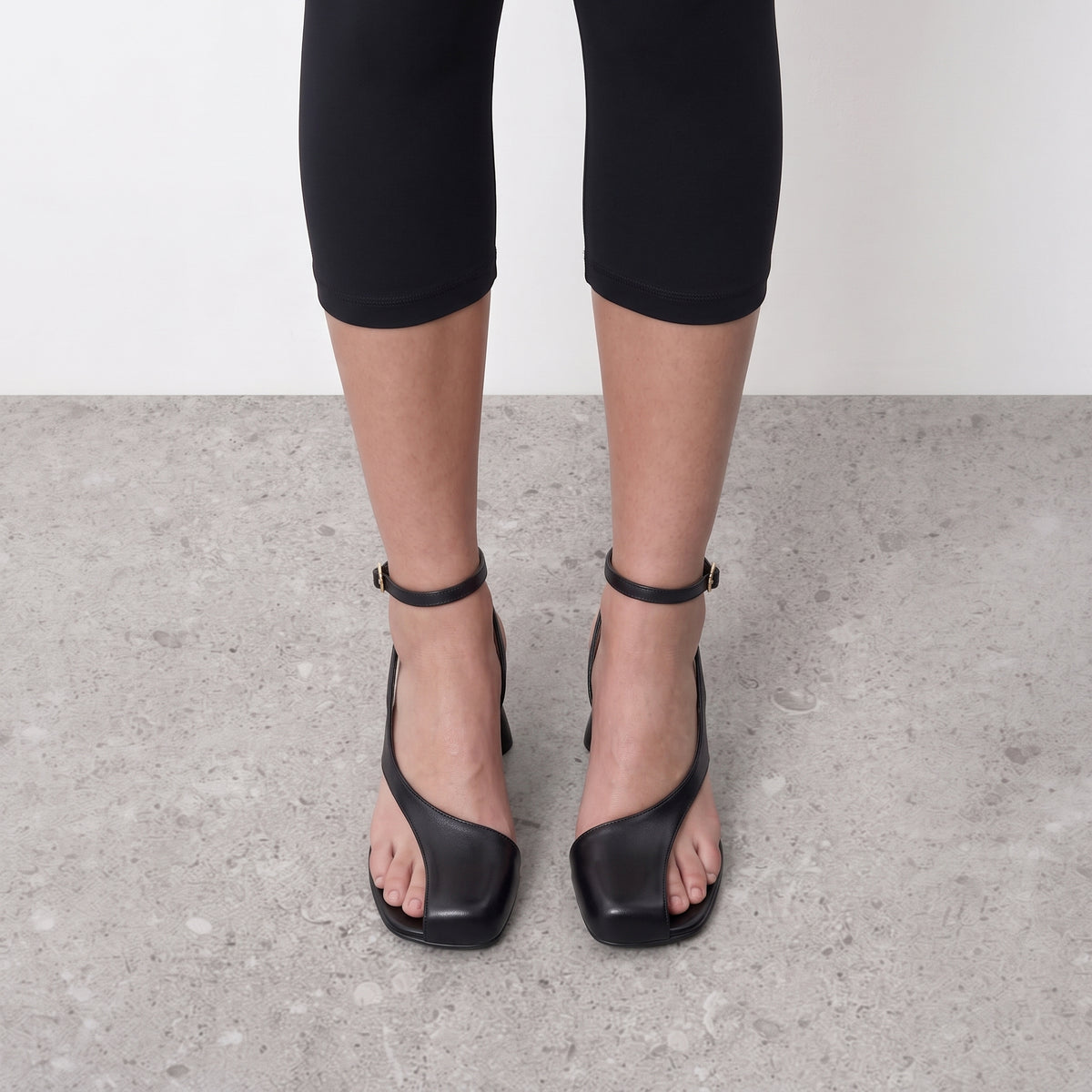 Front view on the foot of black strappy sandals with a square open toe