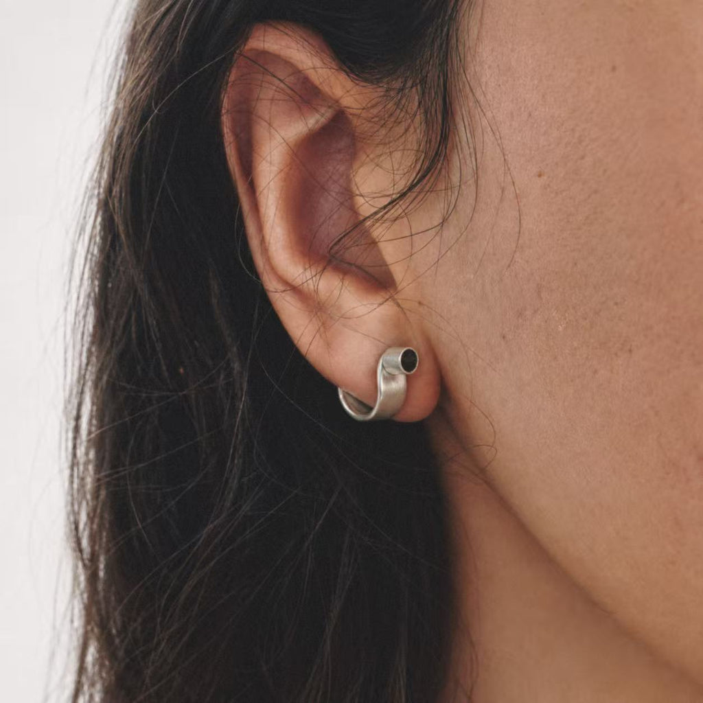 Model wearing the Pebble Disc Huggie Earrings seen from the side