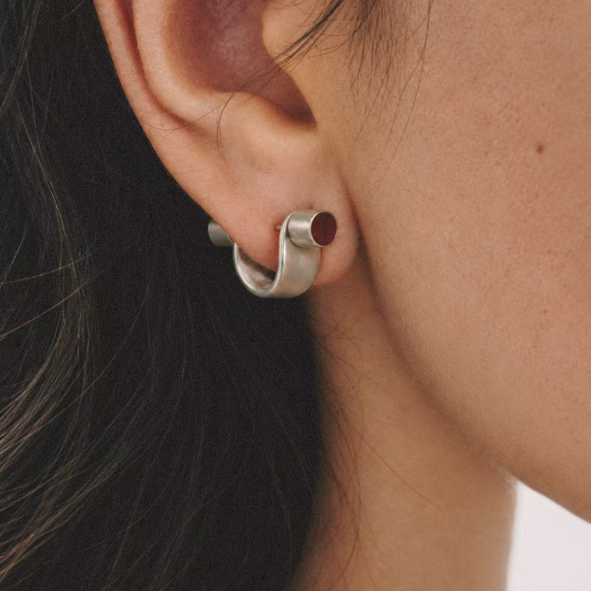 Model wearing the Pebble Disc Huggie Earrings in a relaxed pose
