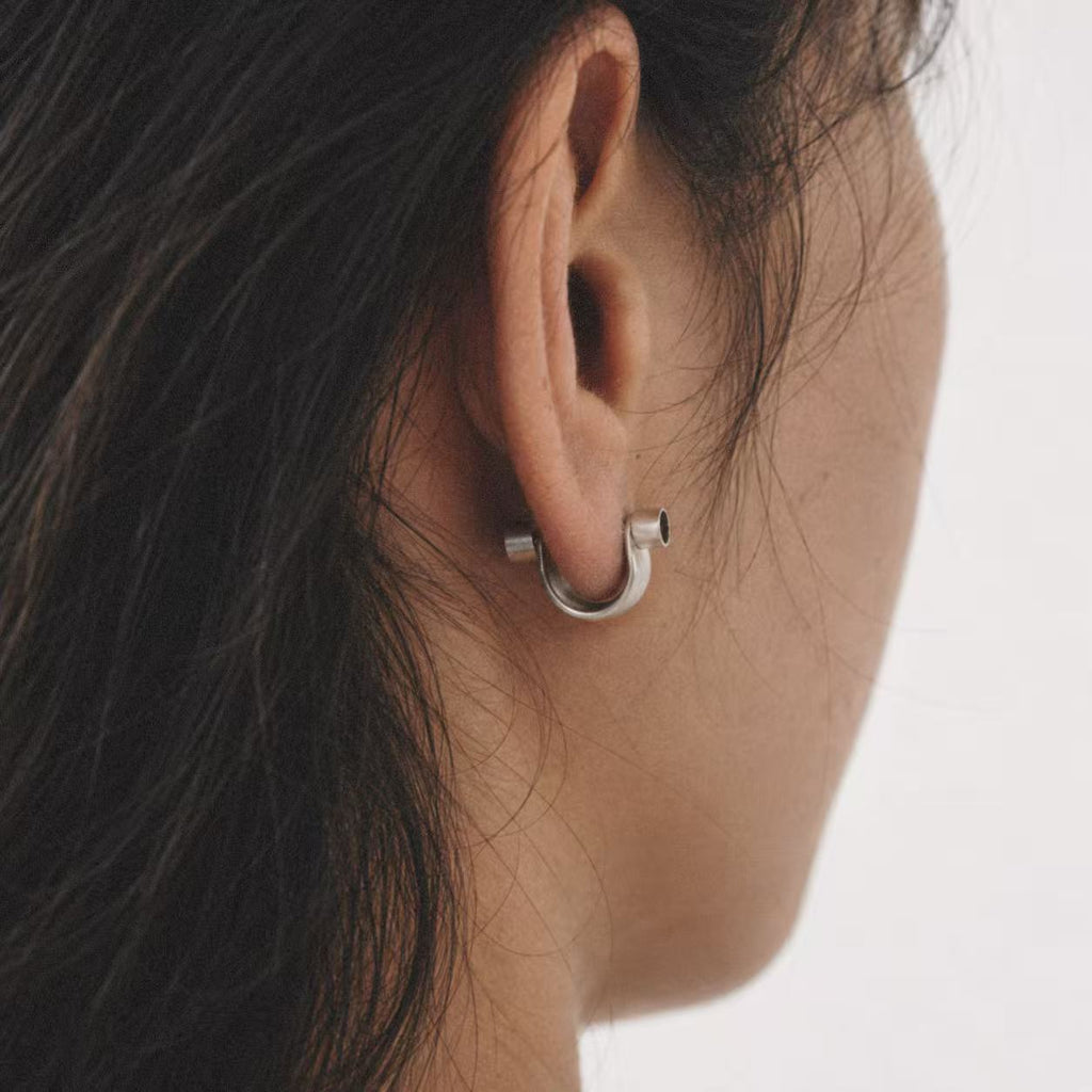 Model wearing the Pebble Disc Huggie Earrings from a low angle
