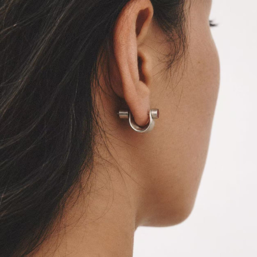 Model wearing the Pebble Disc Huggie Earrings in a detail shot
