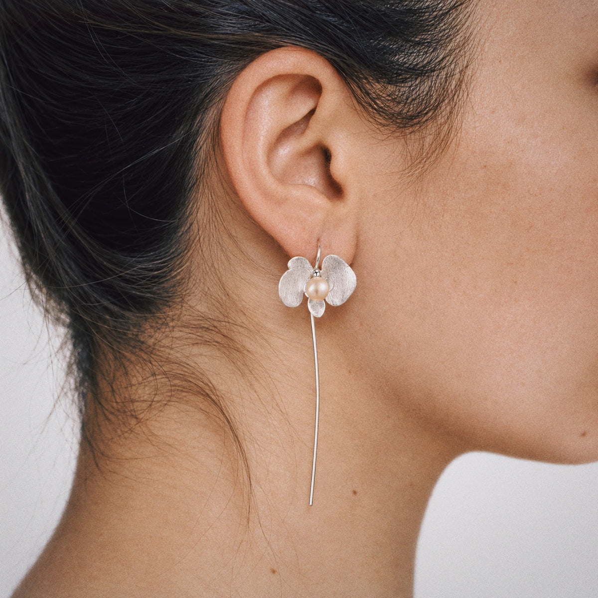Petal Orchid Drop Earrings styled on the ear with a plain black outfit