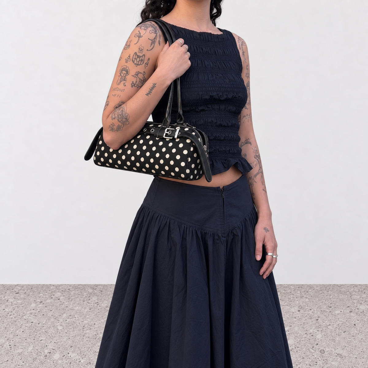 Model carrying the black polka dot baguette bag under the arm