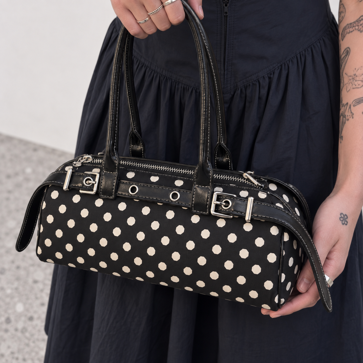Close view of the polka dot baguette bag worn with a black outfit