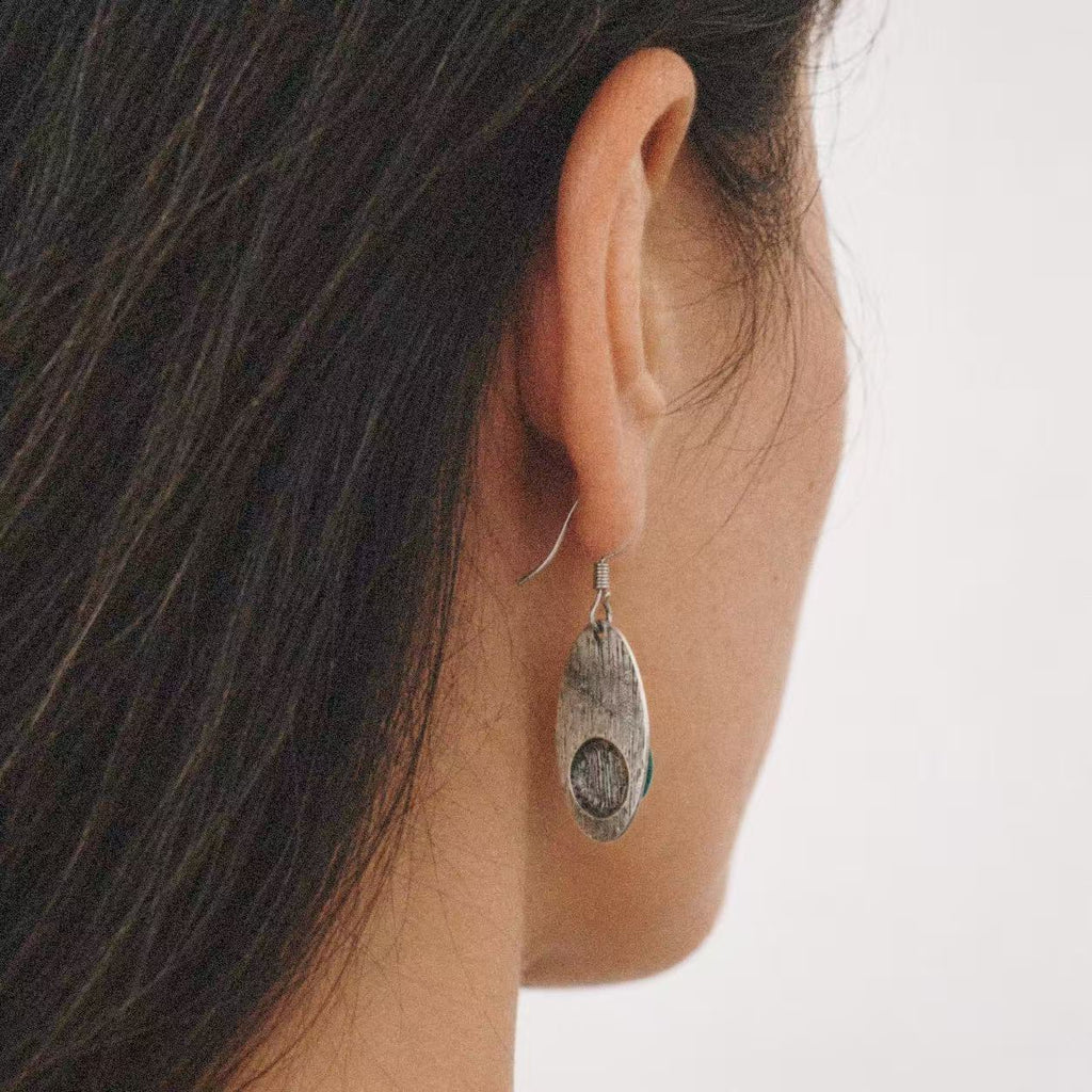 Relic Green Stone Drop Earrings styled on the ear with a plain black outfit
