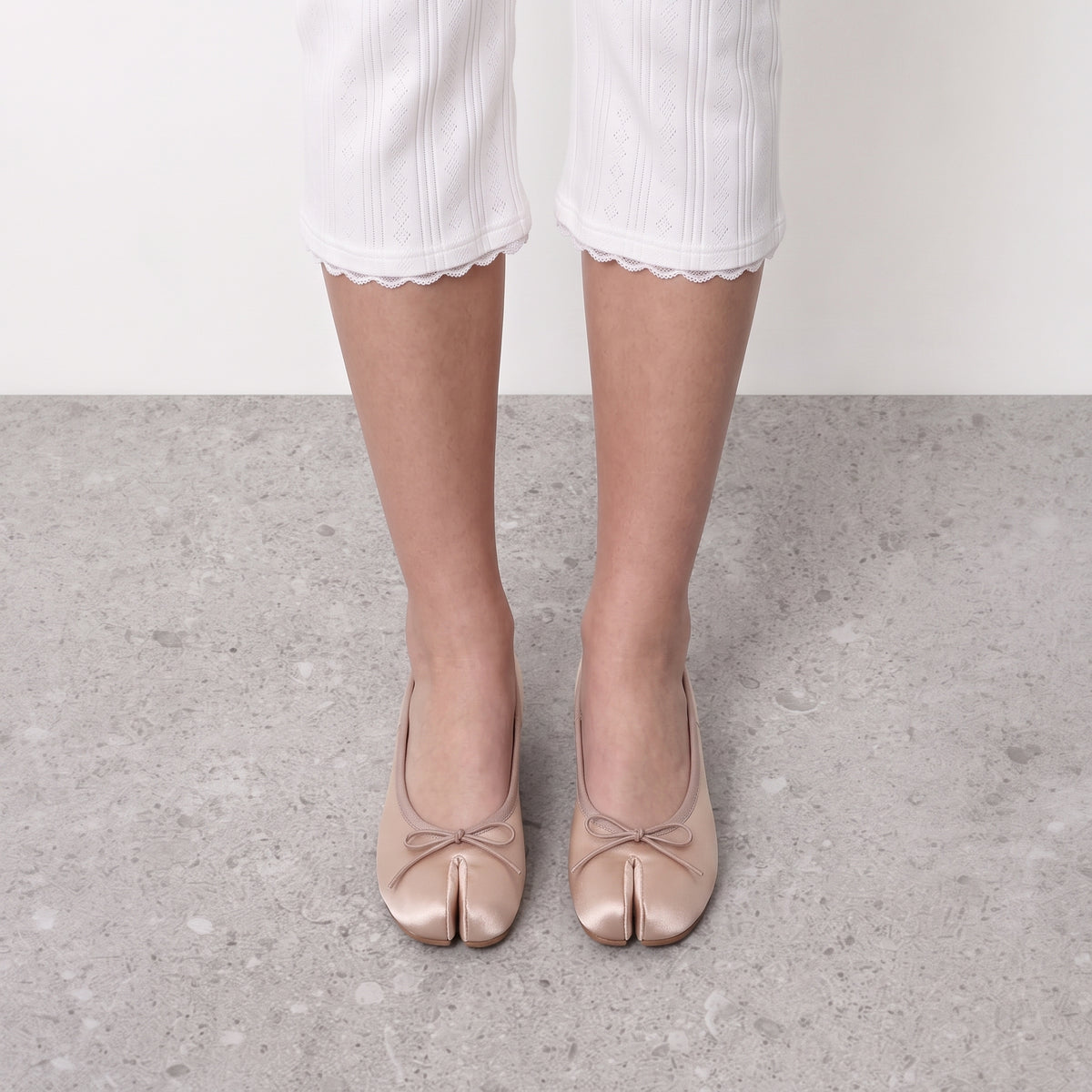 Front view on the foot of champagne tabi pumps showing the divided toe and bow