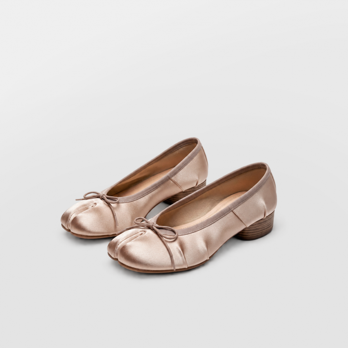 Pair of champagne satin tabi ballerina pumps angled on a white background
