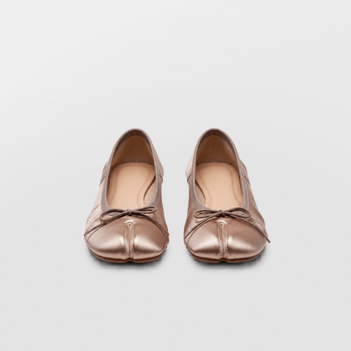 Front view of both champagne tabi pumps showing the split toe seam and cord bows
