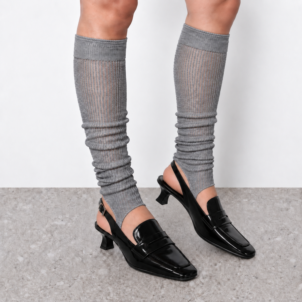 Model wearing grey ruched stirrup leg warmers over slingback heels seen from the side