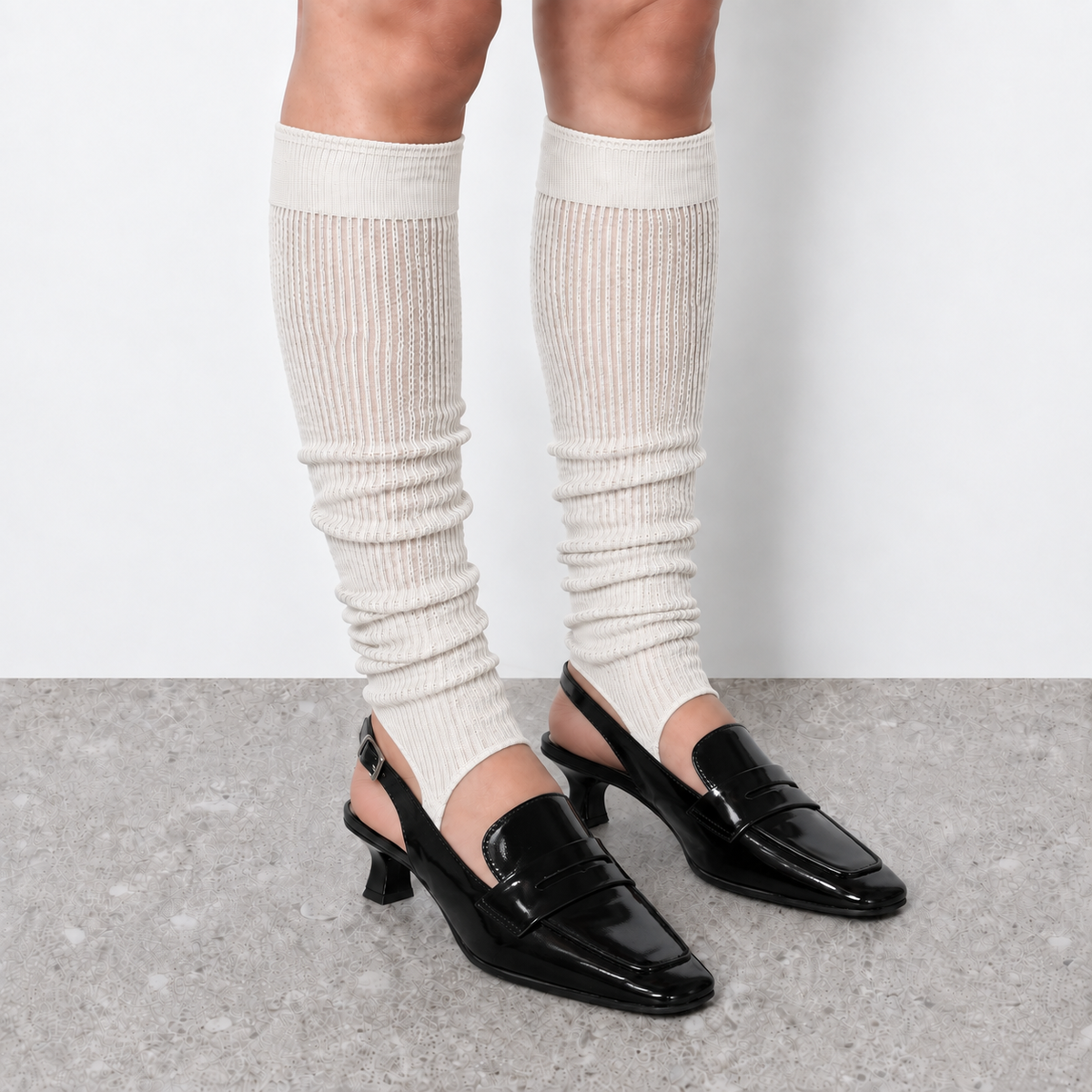 Model wearing white ruched stirrup leg warmers over slingback heels seen from the front